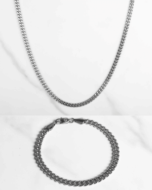 Ett silverfärgat Pansarlänk set silver 5mm halsband och matchande armband visas på en vit yta och framhäver deras eleganta, polerade curb-link design.