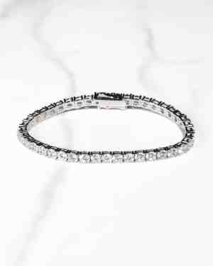 Ett tennisarmband i silver, 4 mm, med en rad gnistrande rundskurna diamanter, på en vit marmoryta.